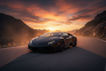 Black Lamborghini Huracán on mountain road at sunset